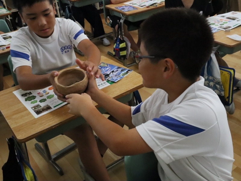 貝塚から発掘される土器（レプリカ）を触ってみる