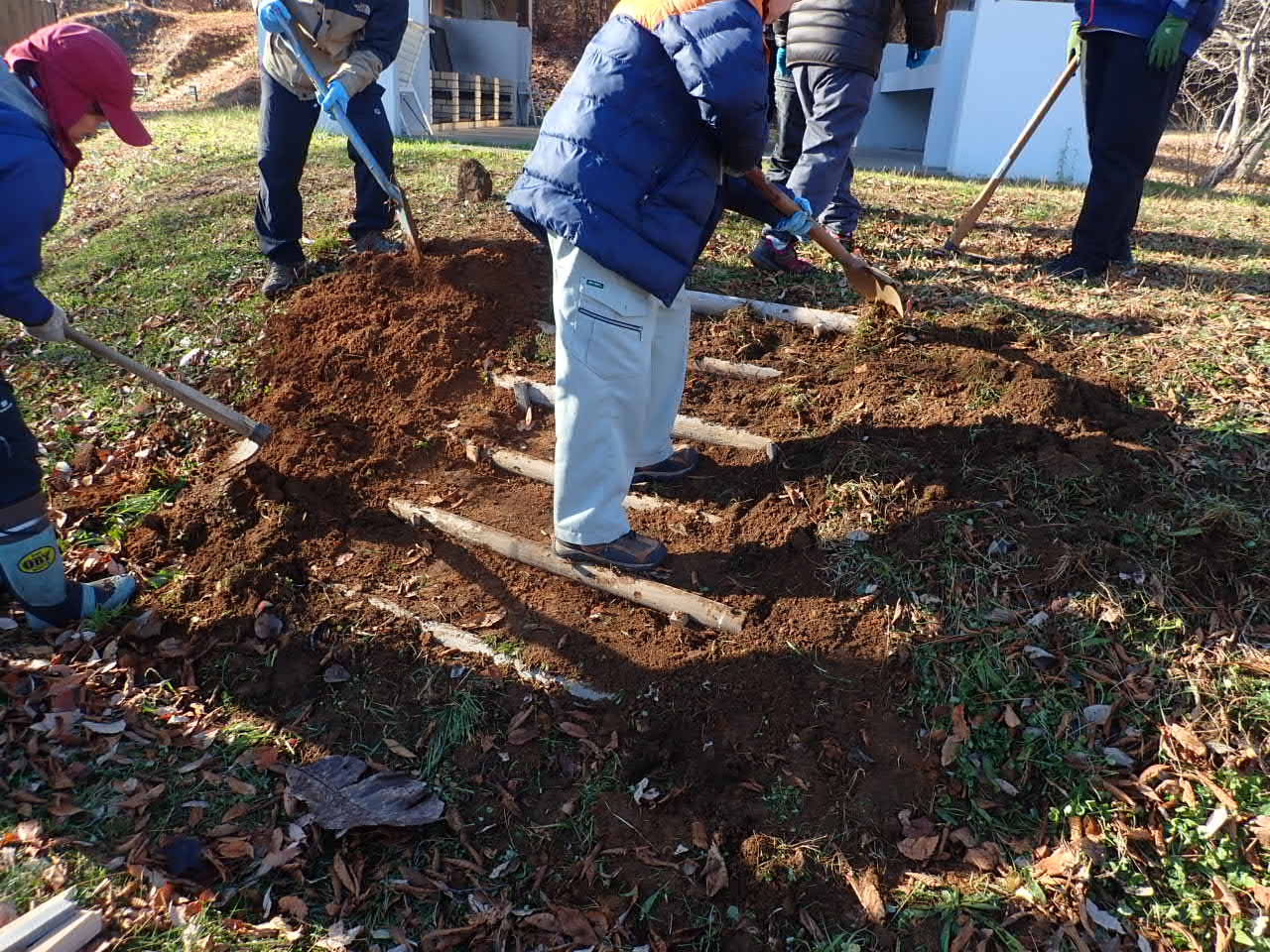 ３段目の階段の土をスコップで均しているボランティア